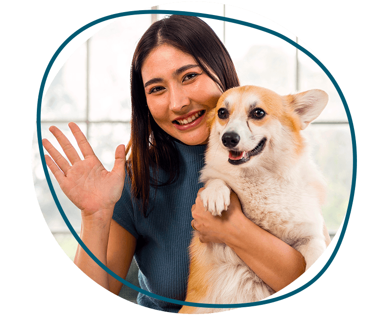 woman waves while holding her corgi dog